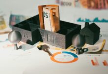 hand holding house keys beside calculator and money for mortgage escrow refund article
