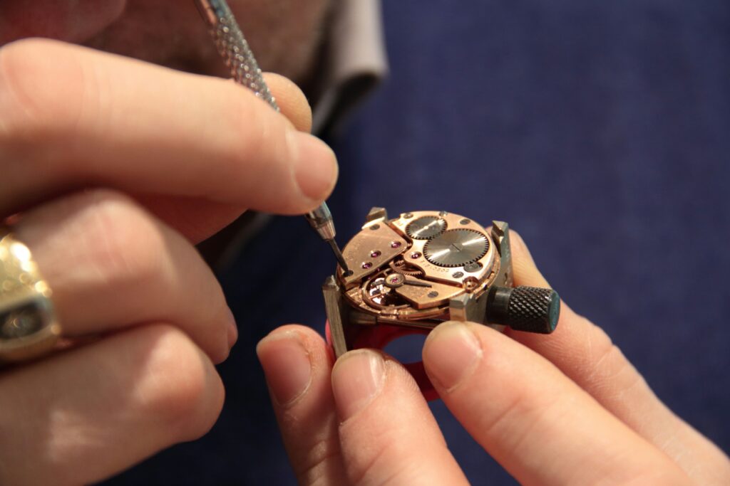 Watchmaker using precision tools to assemble a luxury mechanical watch movement.